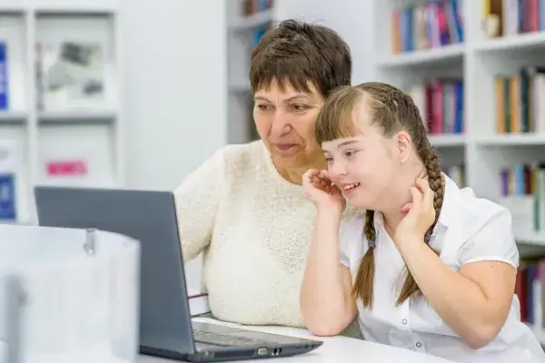 A Down syndrome girl with a foster mother looking at a laptop